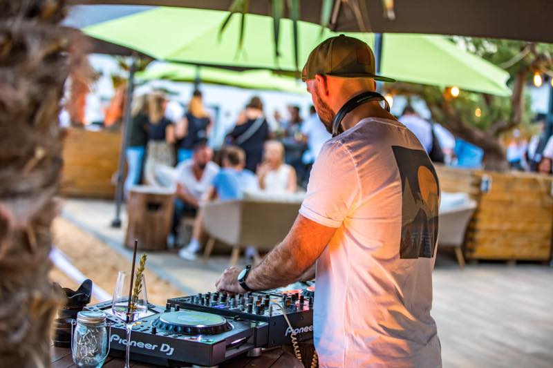 DJ am Plattenteller unter grünem Sonnenschirm