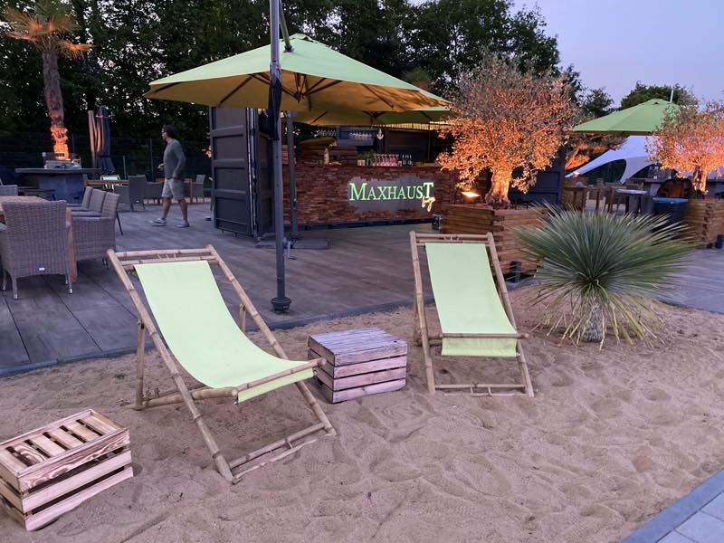 Zwei Liegestühle im Sand vor dem Barcontainer im Abendlicht