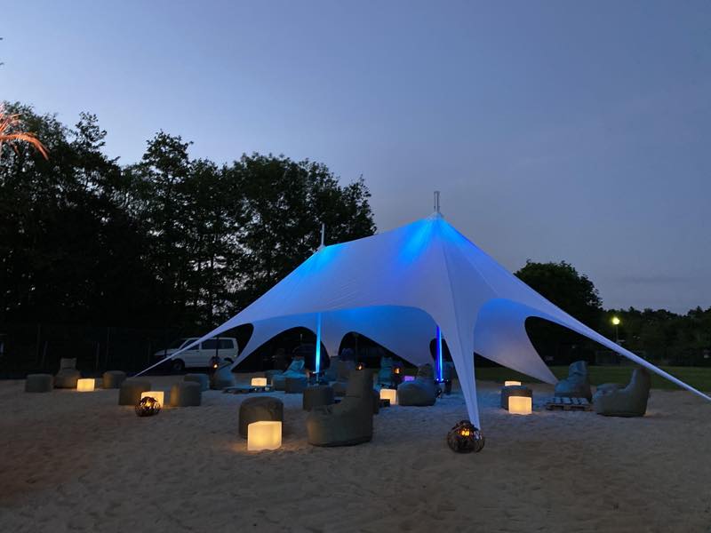 Beleuchtetes Sternzelt mit Sitzsäcken und Windlichtern am Abend