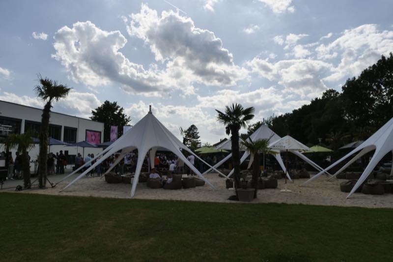Sternzelte im Sandbereich unter Wolkenhimmel, davor die Wiese