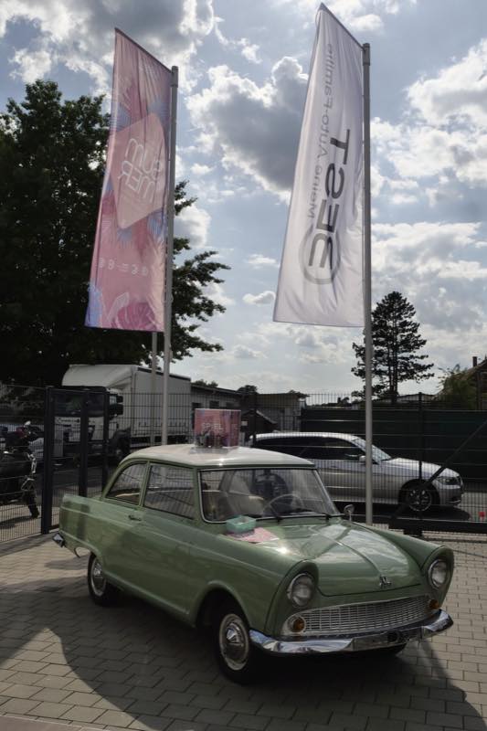 Oldtimer als Hingucker zwischen Werbefahnen beim Sommerfest