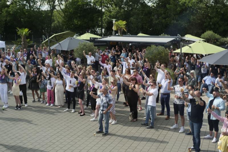 Große Gästegruppe stößt beim Firmensommerfest gemeinsam an