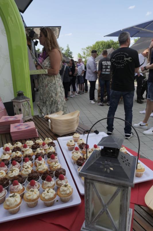 Cupcakes und Servietten auf dem Buffettisch, dahinter Gäste