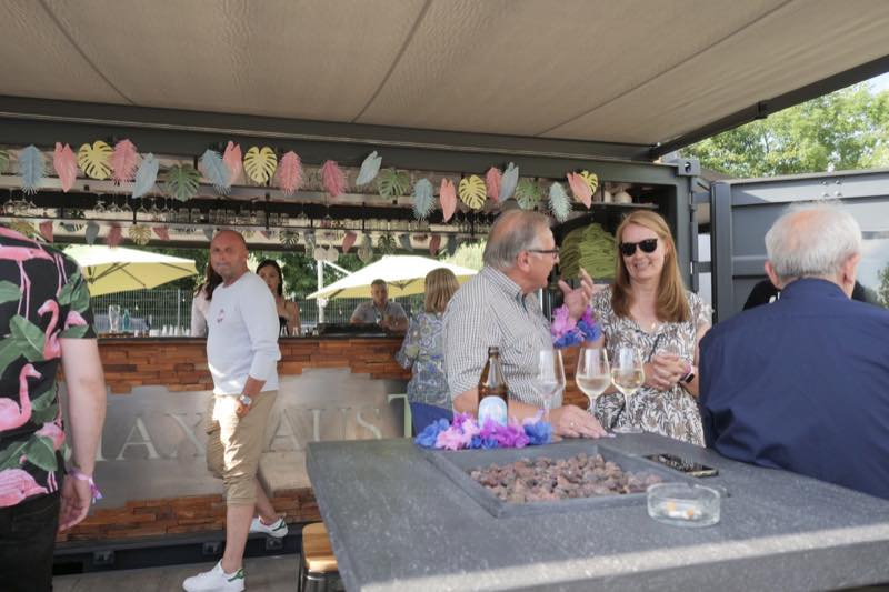 Gäste am Feuertisch vor dem Barcontainer mit Sommerdeko