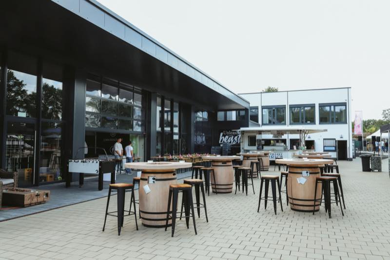 Fasstische mit Barhockern auf dem Platz vor dem Gebäude