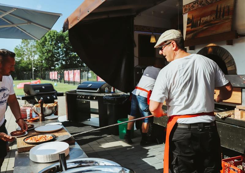 Pizzabäcker schiebt eine Pizza in den Holzofen
