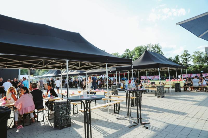 Stehtische und Biertische unter schwarzen Pavillons